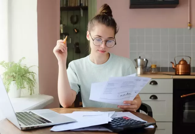 Woman reviewing papers in front of laptop