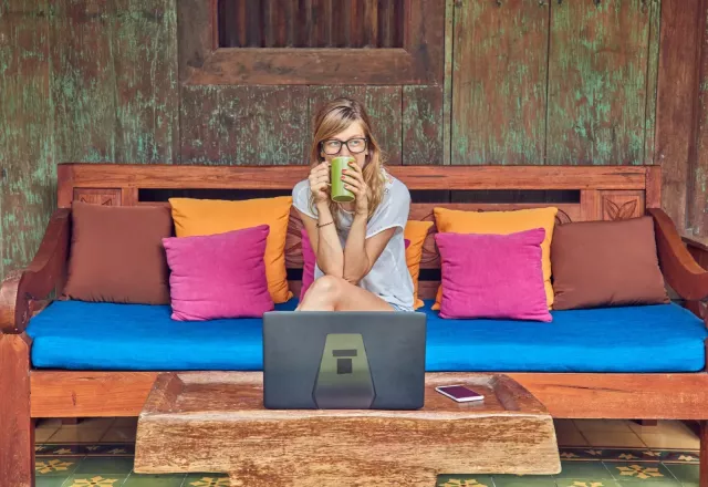 Woman sitting on couch in front of laptop
